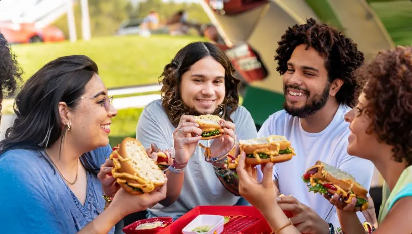 A joyful gathering of friends savoring Oklahoma Onion Smashburgers at an outdoor event